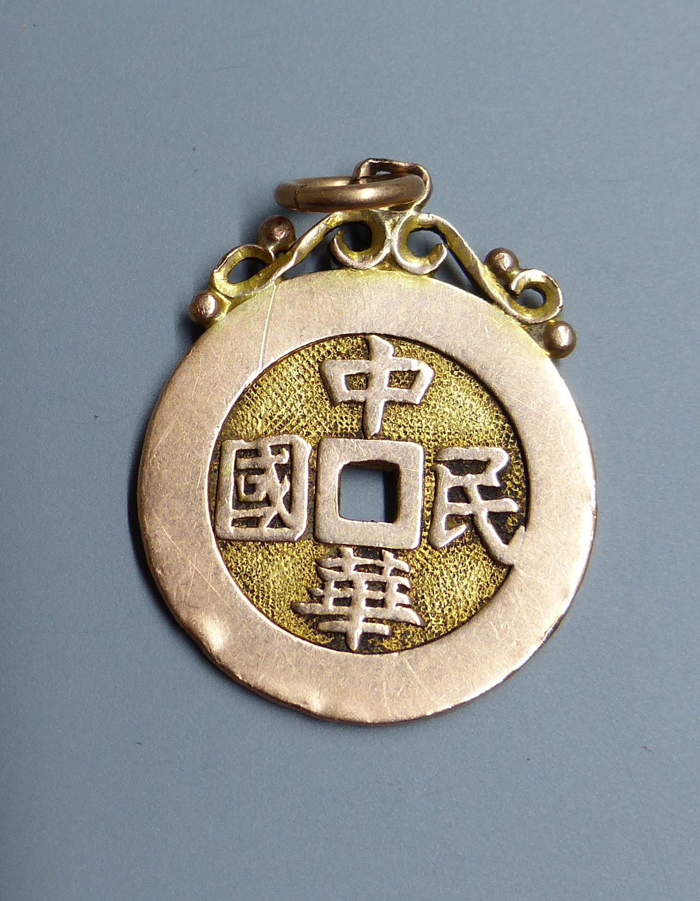 Eight assorted Chinese yellow metal amulets, four in the form of brooches, three pendants and a stick pin, 21.5 grams.